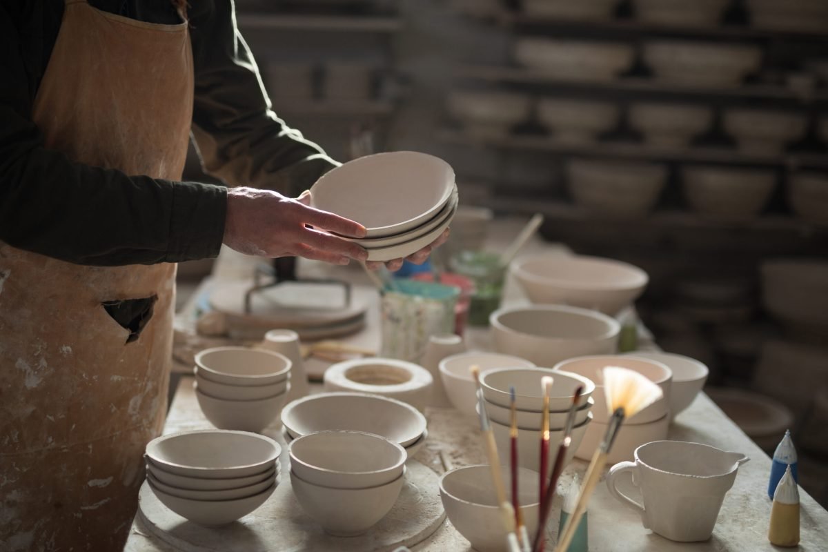 Mid section of male potter holding bowls in pottery workshop